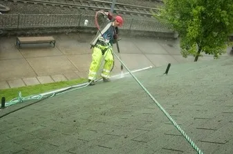 Monte Wallenstein, owner of USA Gutter, Window, & Roof Cleaning, inspecting moss on a Portland roof