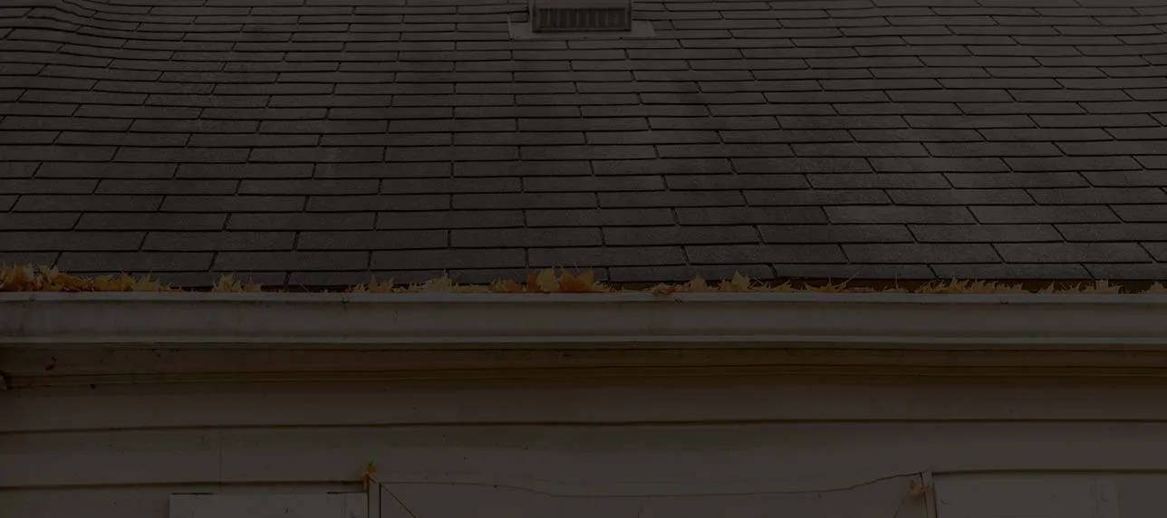 Homeowner on a ladder cleaning gutters on a Portland single-story home